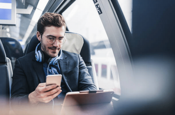 Homme avec un portable et une tablette, assis dans un transport en commun